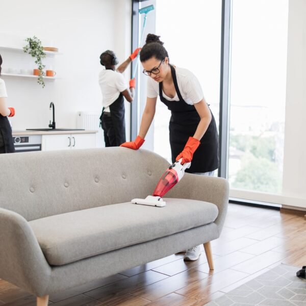 full-length-multiethnic-young-cleaner-vacuuming-sofa